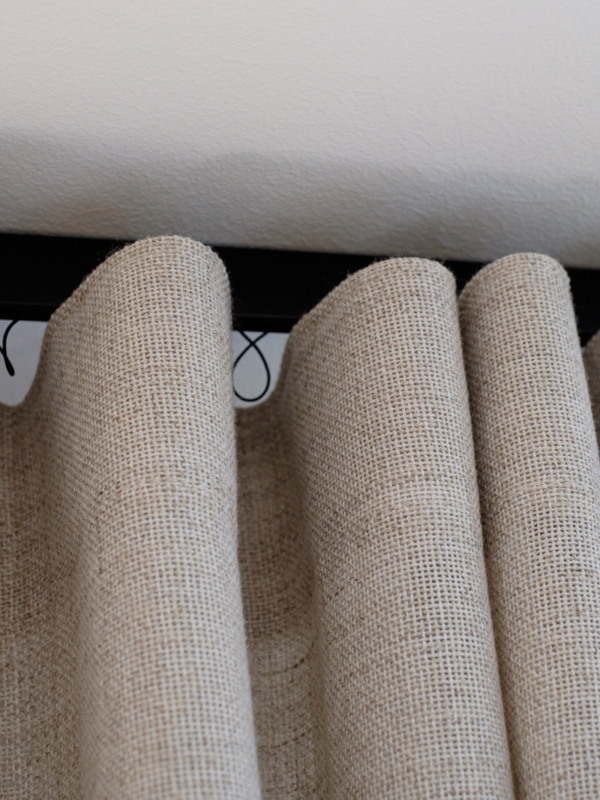 mariel-interior-olohuoneen-verhosuunnittelu-klaukkala-2024-3 Lähikuva mukavan tekstuurisista verhoista ja mattamustista kiskoista.