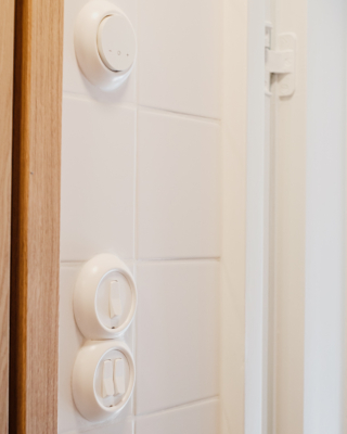 Retro-tyyppiset valokatkaisijat ja termostaatti istuvat vanhaan kylpyhuoneeseen.