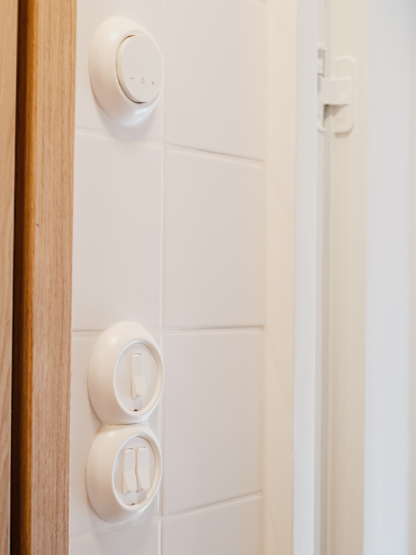 Retro-tyyppiset valokatkaisijat ja termostaatti istuvat vanhaan kylpyhuoneeseen.